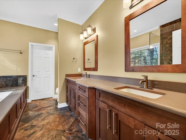 a spacious bathroom with a granite countertop double vanity sink a mirror and a shower