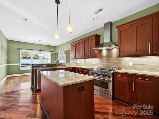 a kitchen with stainless steel appliances granite countertop a stove a sink dishwasher and a refrigerator with wooden cabinets