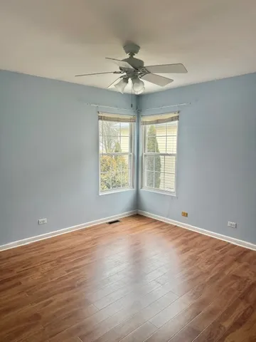 a view of an empty room with window and wooden floor