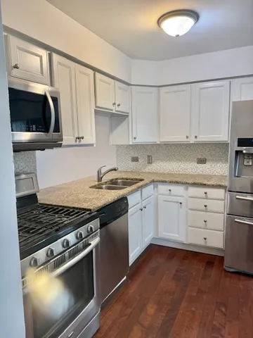 a kitchen with stainless steel appliances granite countertop a stove a sink and a microwave
