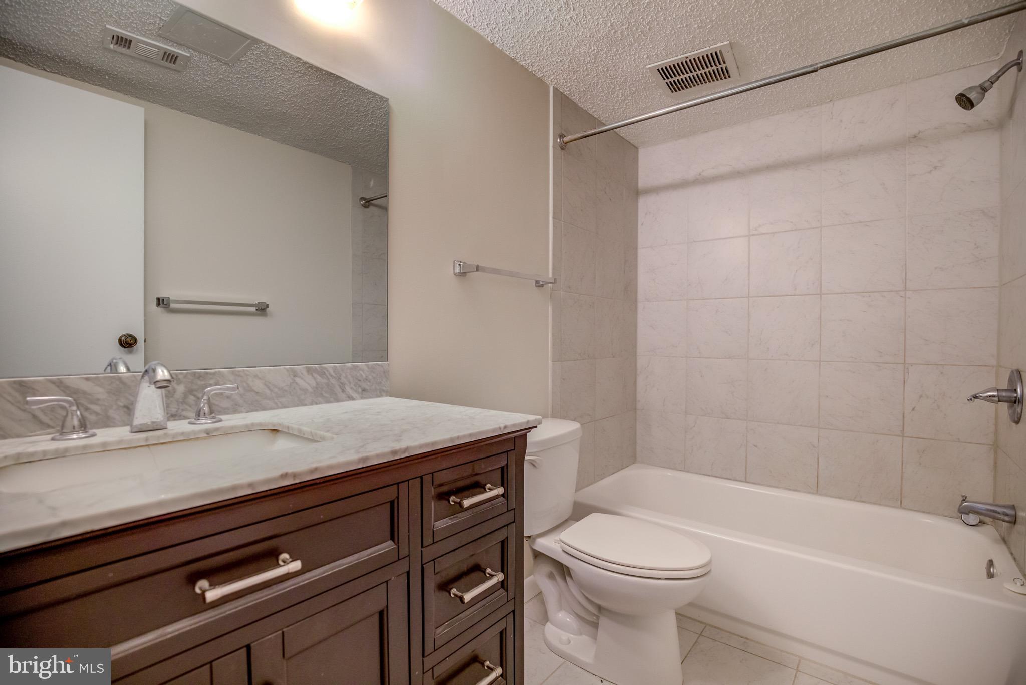 11813 Breton Court, Unit 2B Reston, VA 20191 - Photo 10 of 17 a bathroom with a granite countertop sink toilet and shower