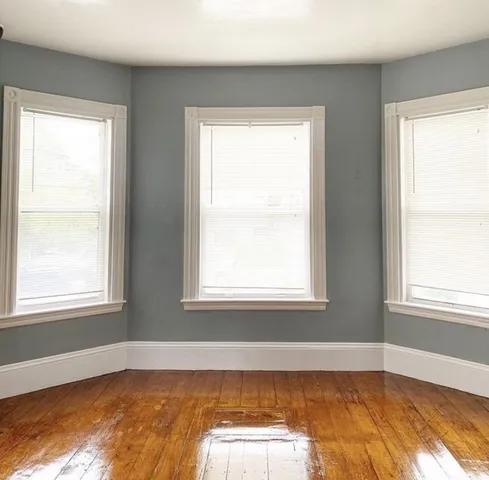 an empty room with wooden floor windows and cabinet