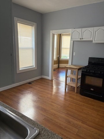 52 Harvest Street, Unit 1 Boston, MA 02125 - Photo 13 of 35 an empty room with wooden floor windows and cabinet