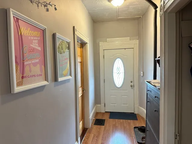 a view of a hallway with wooden floor cabinet and a mirror