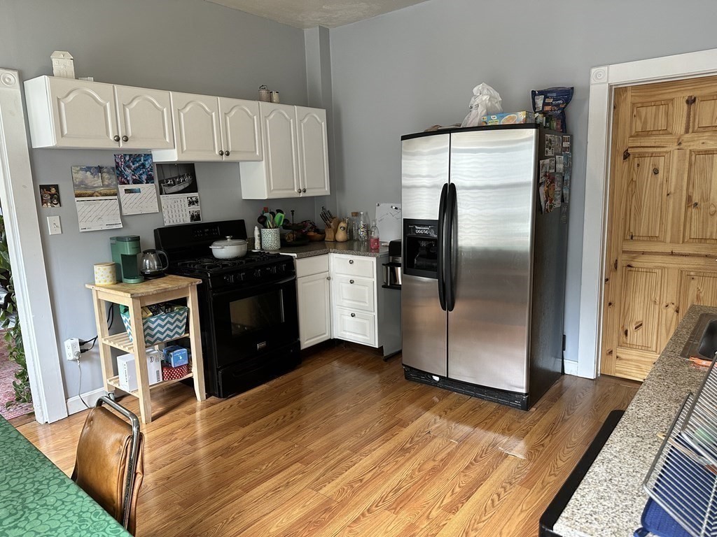 52 Harvest Street, Unit 1 Boston, MA 02125 - Photo 6 of 35 a kitchen with stainless steel appliances a refrigerator a stove a sink dishwasher and white cabinets with wooden floor