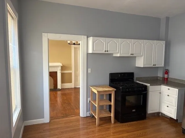 a kitchen with stainless steel appliances a stove a sink and white cabinets with wooden floor