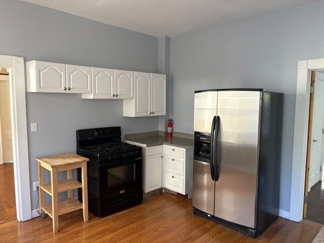 52 Harvest Street, Unit 1 Boston, MA 02125 - Photo 8 of 35 a kitchen with stainless steel appliances granite countertop a stove a refrigerator and a wooden cabinets