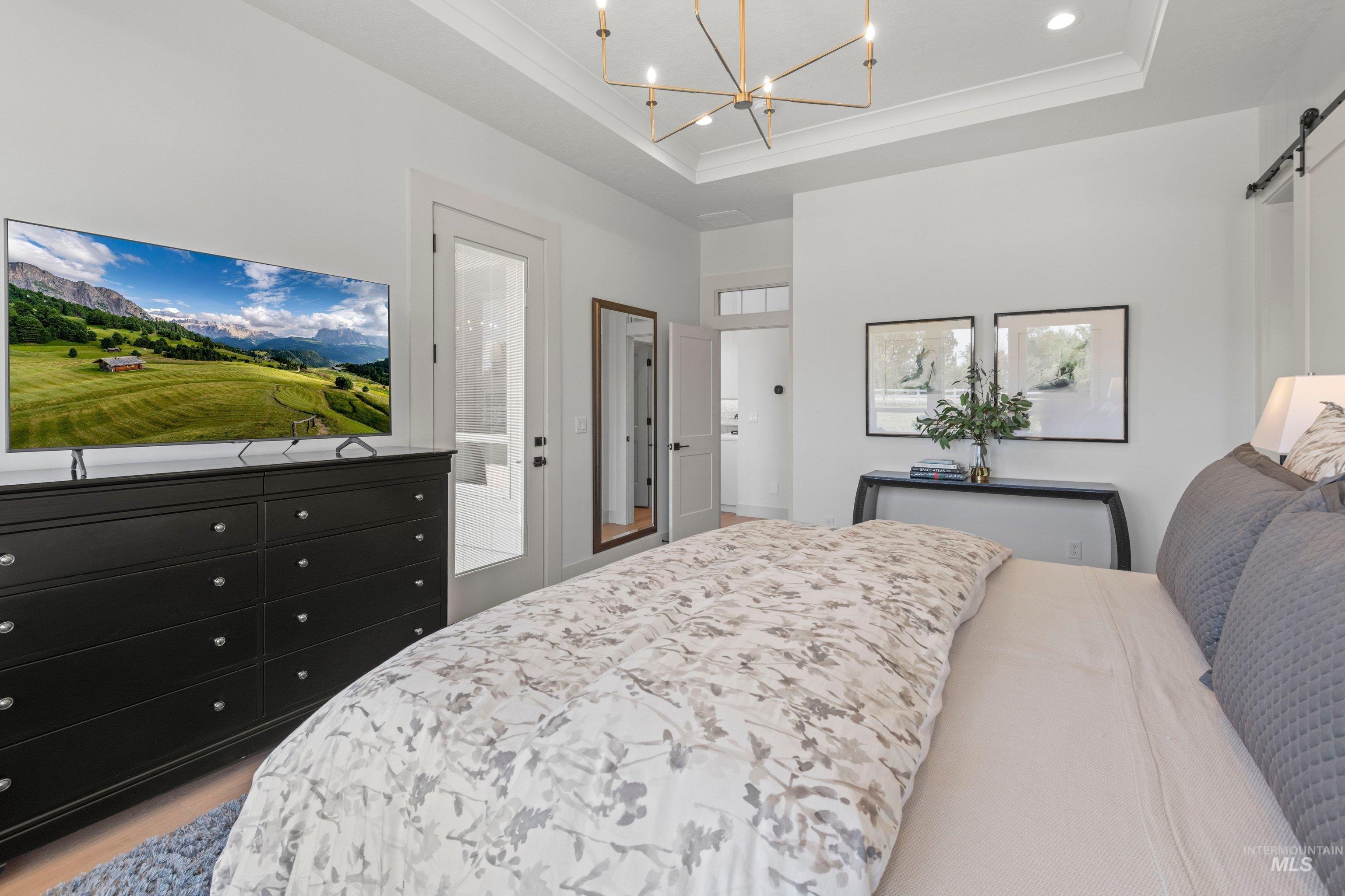 24990 Belgian Way Middleton, ID 83644 - Photo 23 of 50 Spacious room featuring a tray ceiling with a contemporary chandelier, white walls, and light wood-finish flooring