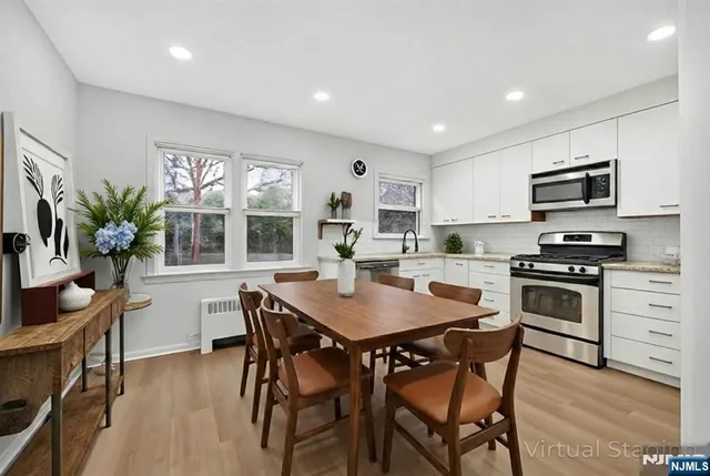 a kitchen with stainless steel appliances a dining table chairs stove refrigerator and microwave