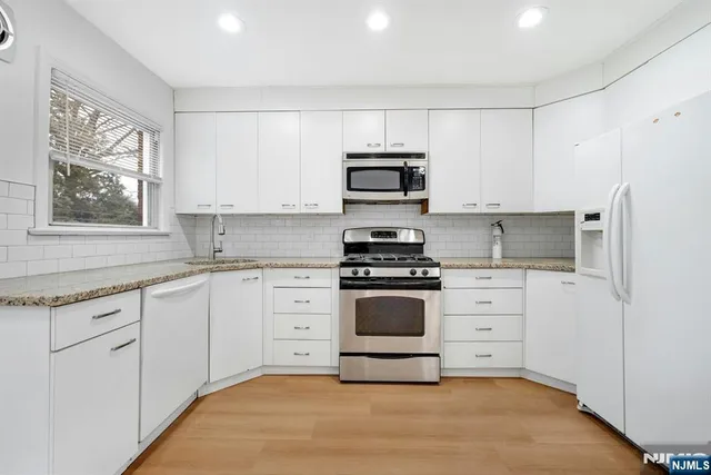 a kitchen with granite countertop white cabinets and stainless steel appliances