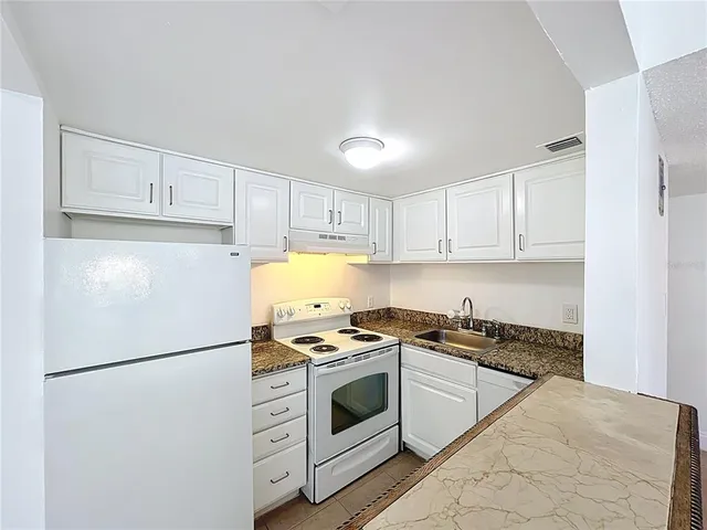 a white refrigerator freezer and a stove in a kitchen