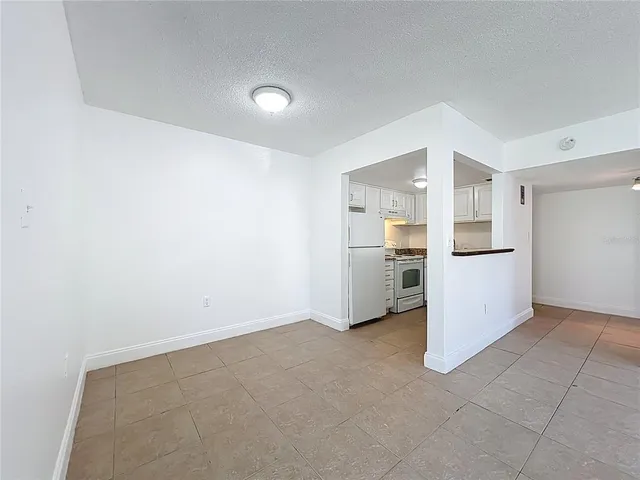 an empty room with a kitchen and a refrigerator