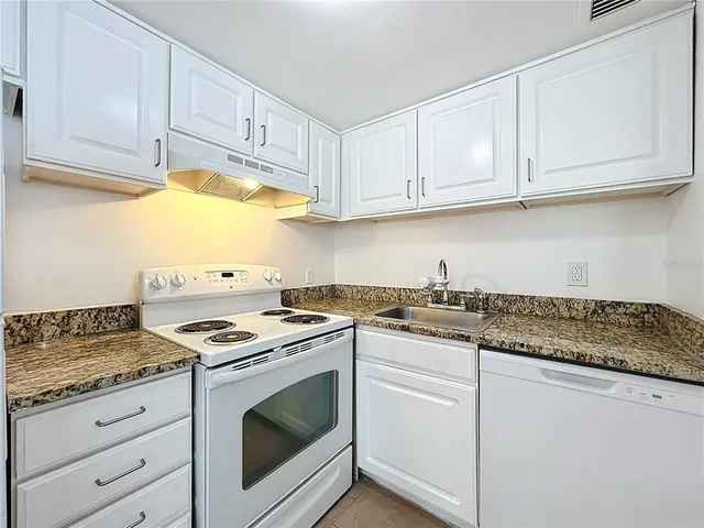 a kitchen with granite countertop white cabinets and white appliances