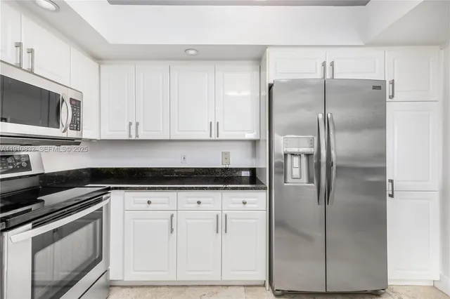 a kitchen with granite countertop a refrigerator sink and cabinets
