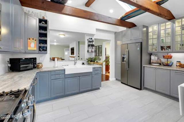 a large kitchen with stainless steel appliances kitchen island granite countertop a refrigerator and a sink
