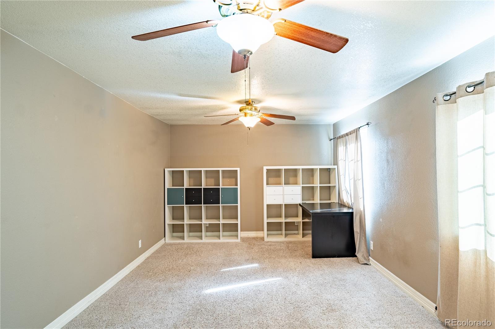 1124 Newark Street Aurora, CO 80010 - Photo 18 of 32 an empty room with chandelier fan and windows