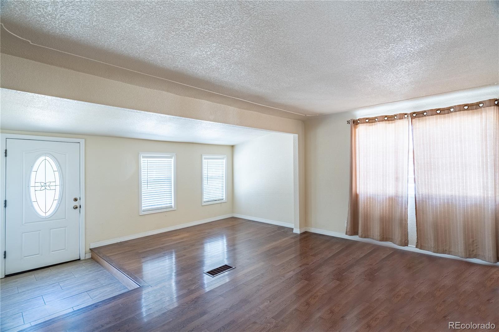 1124 Newark Street Aurora, CO 80010 - Photo 3 of 32 an empty room with wooden floor mirror and windows