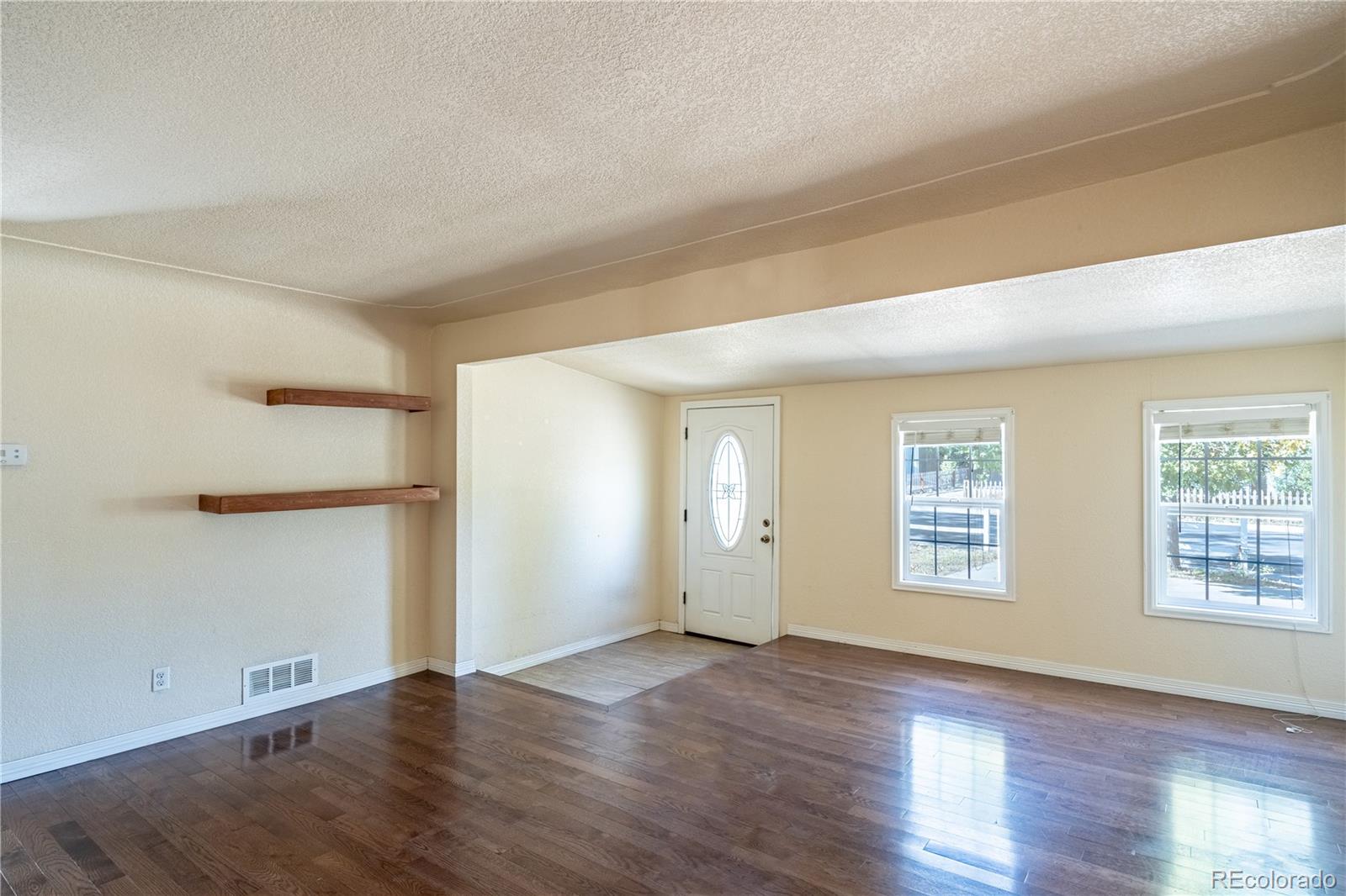 1124 Newark Street Aurora, CO 80010 - Photo 4 of 32 an empty room with wooden floor and windows