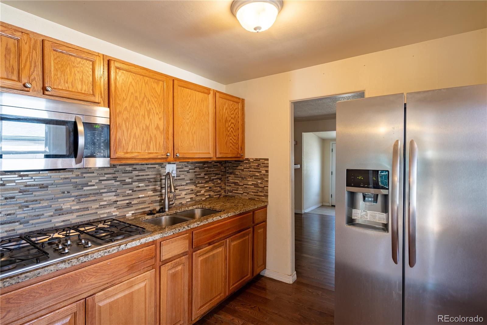 1124 Newark Street Aurora, CO 80010 - Photo 7 of 32 a kitchen with stainless steel appliances granite countertop a refrigerator and a sink