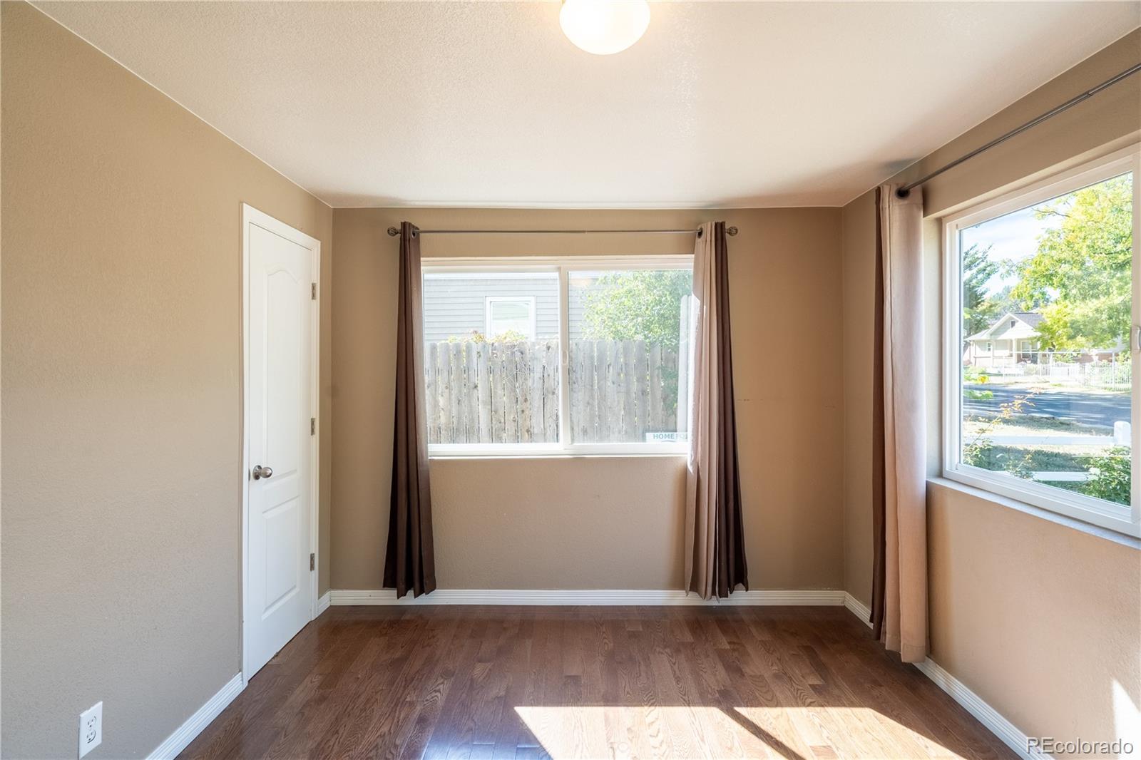 1124 Newark Street Aurora, CO 80010 - Photo 10 of 32 a view of an empty room with wooden floor and a window