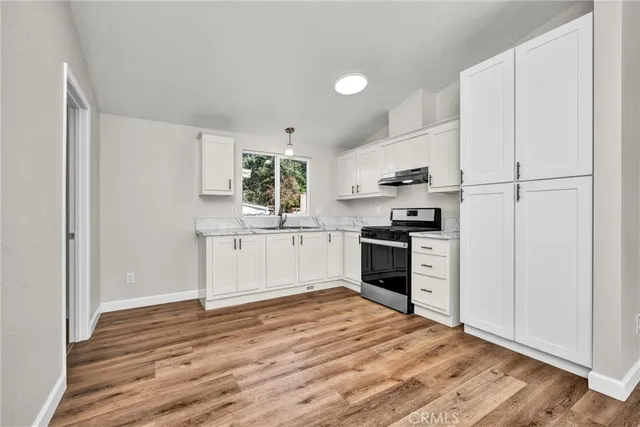 a kitchen with granite countertop a refrigerator stove top oven and sink