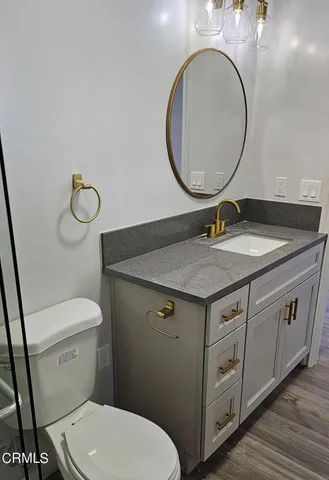 a bathroom with a granite countertop toilet sink and mirror