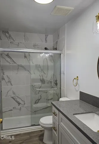 a bathroom with a granite countertop sink a toilet and shower