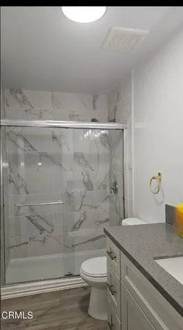 a bathroom with a granite countertop sink a toilet and shower