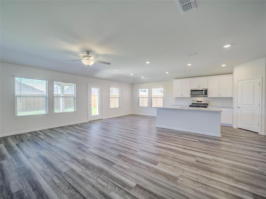 3405 Kingsgarden Road Denton, TX 76207 - Photo 9 of 37 a view of an empty room with wooden floor and a kitchen