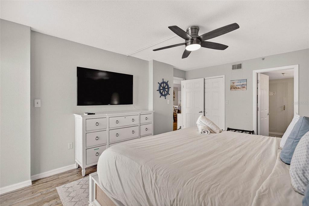 14300 Gulf Boulevard, Unit 104 Madeira Beach, FL 33708 - Photo 22 of 42 a bedroom with a bed a flat screen tv and a chandelier