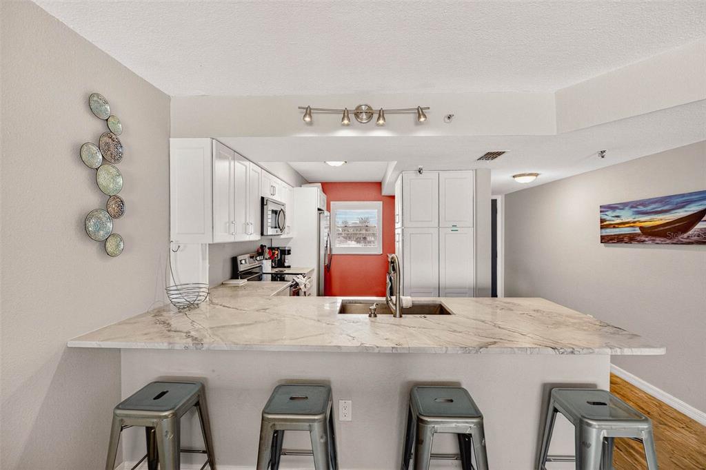 14300 Gulf Boulevard, Unit 104 Madeira Beach, FL 33708 - Photo 4 of 42 a kitchen with kitchen island a dining table and chairs