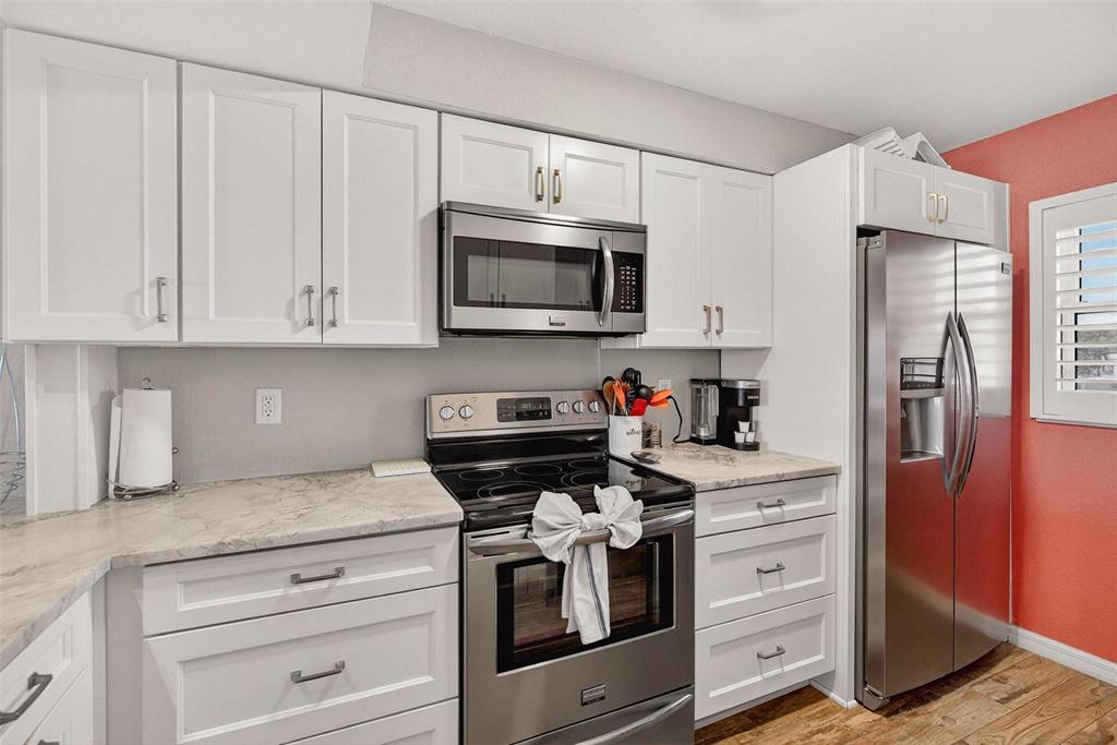 14300 Gulf Boulevard, Unit 104 Madeira Beach, FL 33708 - Photo 9 of 42 a kitchen with granite countertop white cabinets and stainless steel appliances