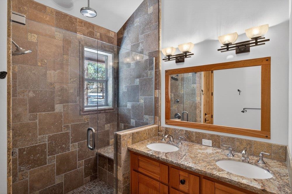 15043 Wolfgang Road Truckee, CA 96161 - Photo 10 of 28 a bathroom with a granite countertop sink a mirror and a shower