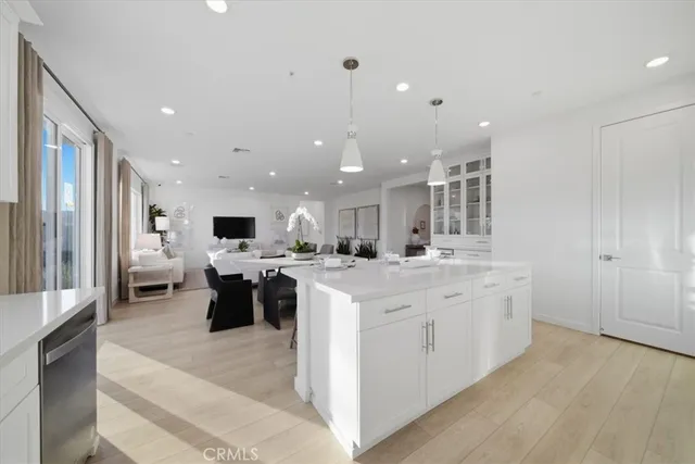 a large kitchen with kitchen island a sink a center island stainless steel appliances and a living room view
