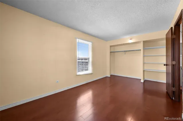 an empty room with wooden floor closet and windows