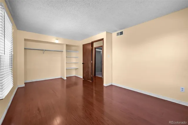 a view of an empty room with wooden floor and closet
