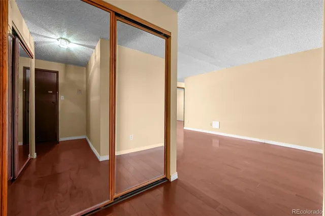 an empty room with wooden floor and mirror