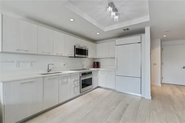 a kitchen with cabinets stainless steel appliances and wooden floor