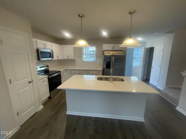 a view of a kitchen with a sink and dishwasher a refrigerator with wooden floor