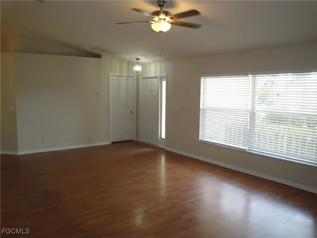a view of an empty room with wooden floor and a window