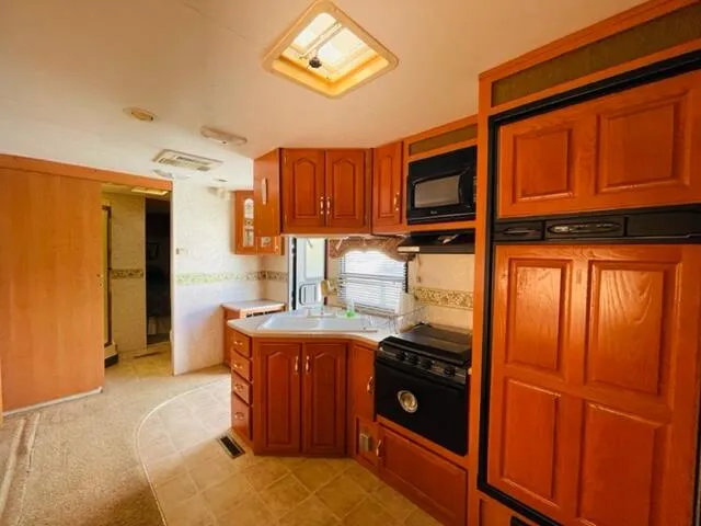 a kitchen with stainless steel appliances granite countertop a refrigerator a stove and a sink with wooden cabinets