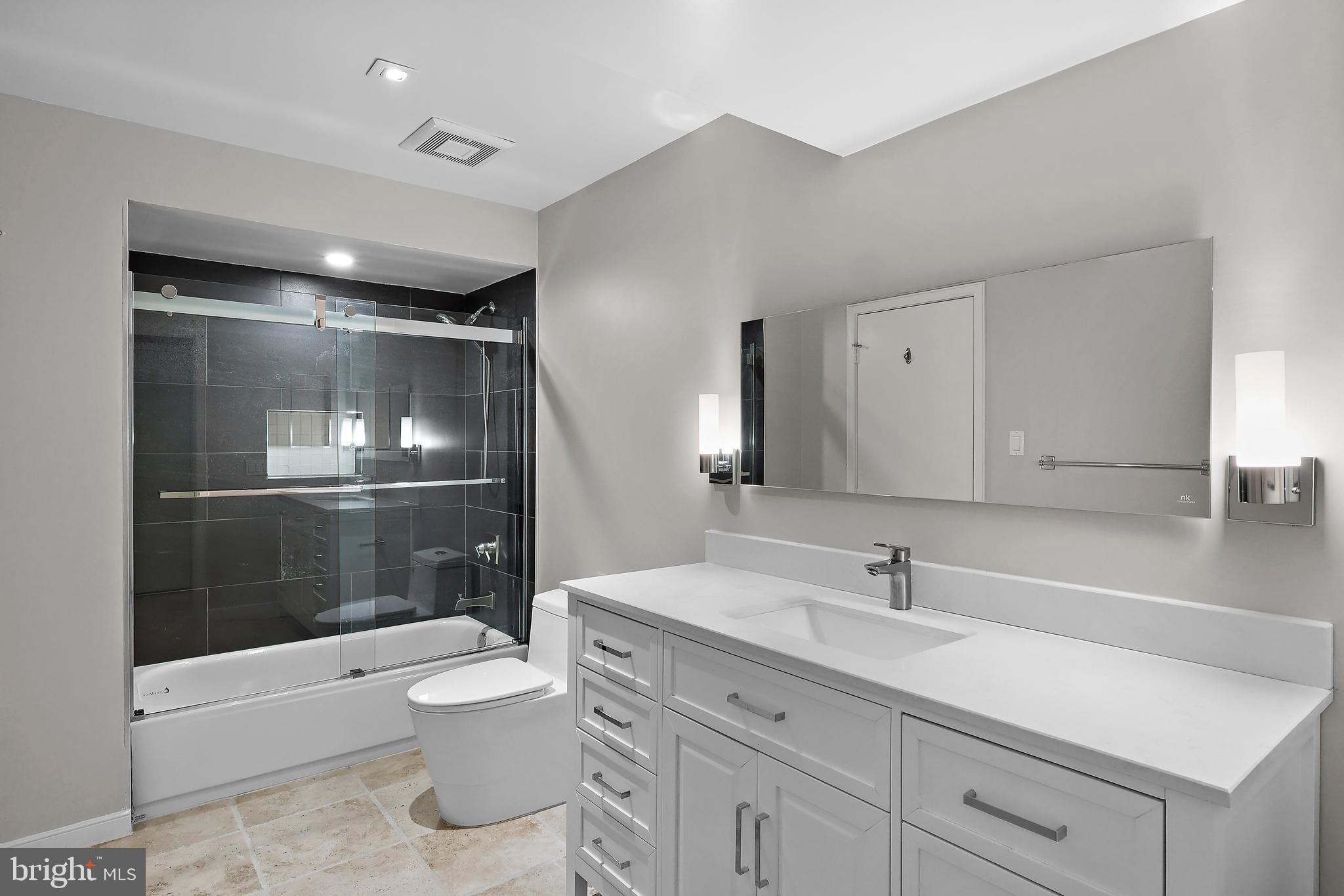 1460 Waterfront Road Reston, VA 20194 - Photo 50 of 63 a bathroom with a toilet a sink a mirror and a glass door shower