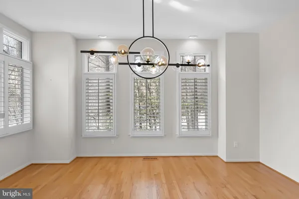a very nice looking room with wooden floor a kitchen view and a chandelier