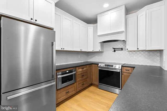 a kitchen with stainless steel appliances white cabinets and a refrigerator