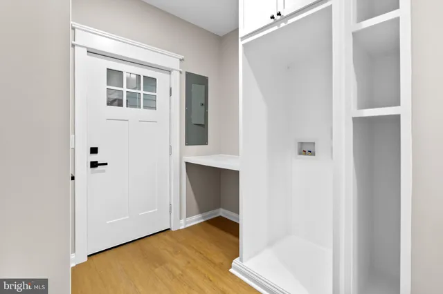 a view of a hallway with wooden floor and a bathroom