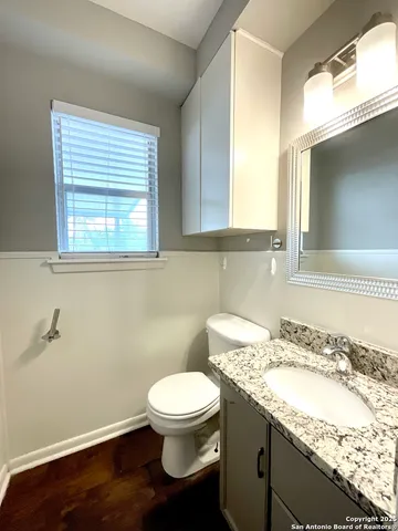 a bathroom with a granite countertop toilet sink and mirror
