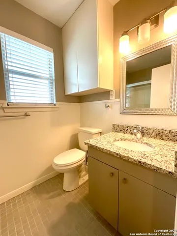 a bathroom with a granite countertop toilet sink and mirror