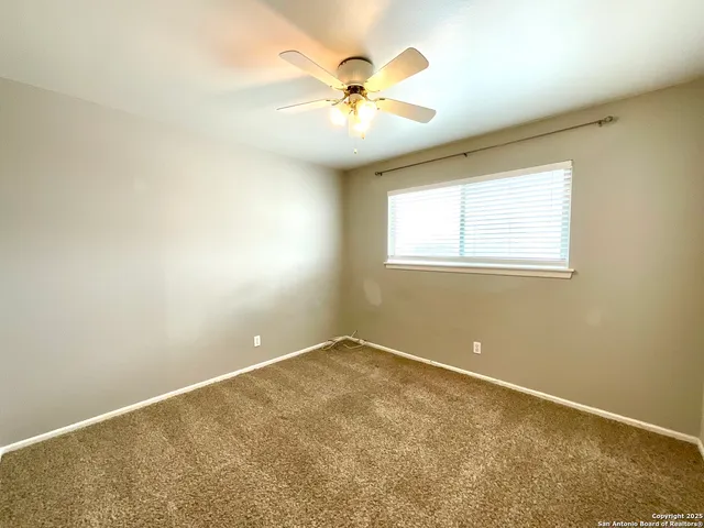 an empty room with a ceiling fan and window