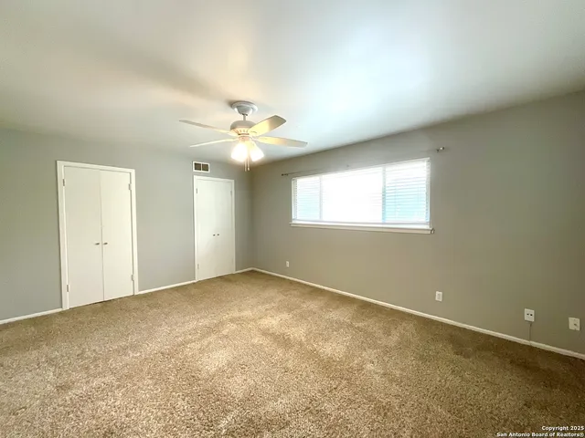 an empty room with windows and chandelier fan
