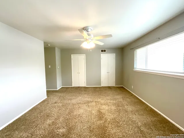 an empty room with windows and ceiling fan